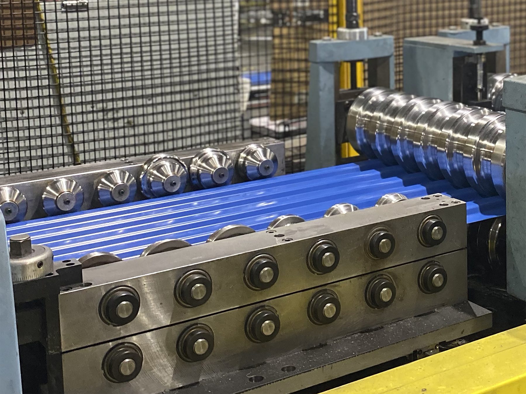 Blue door curtain steel running through a roll former in a Janus manufacturing plant