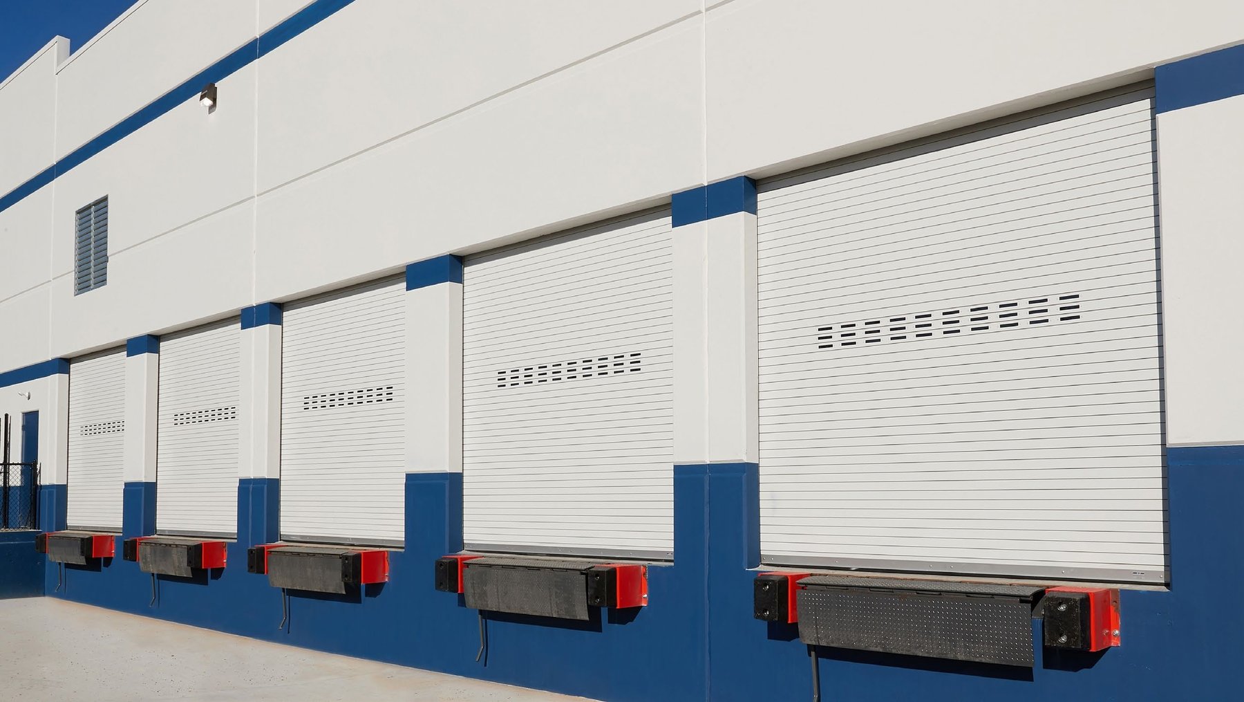 Janus 300 Series rolling slat doors on a white loading dock building