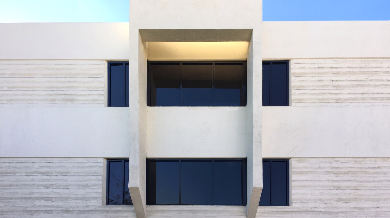White stucco facade with recessed dark faux windows