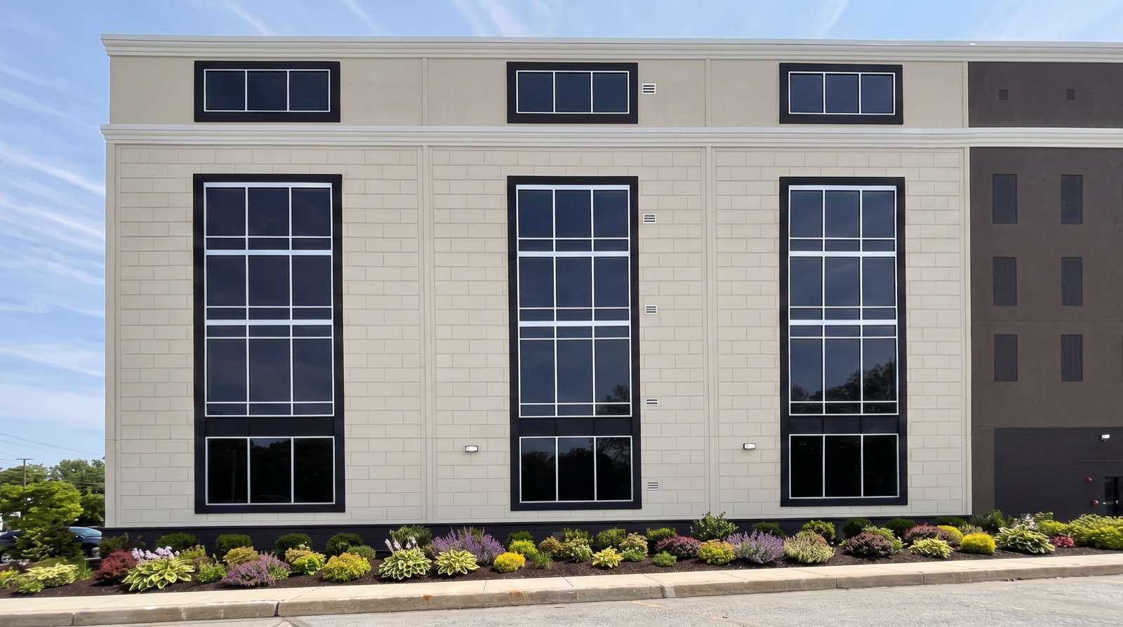 Tall dark-framed faux windows with transoms on a tan block facade