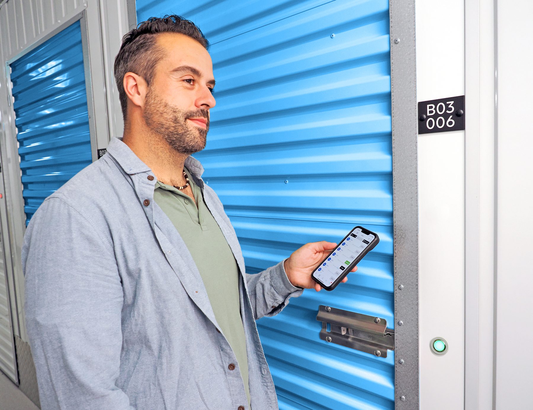 Tenant holding the Nokē app at a self-storage unit with a Nokē Ion smart lock