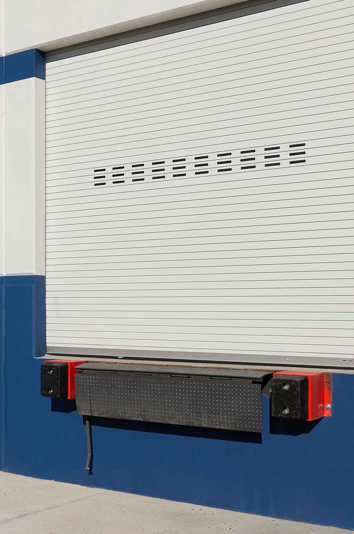 White Janus 300 Series rolling slat door with vision lites above a dock bumper