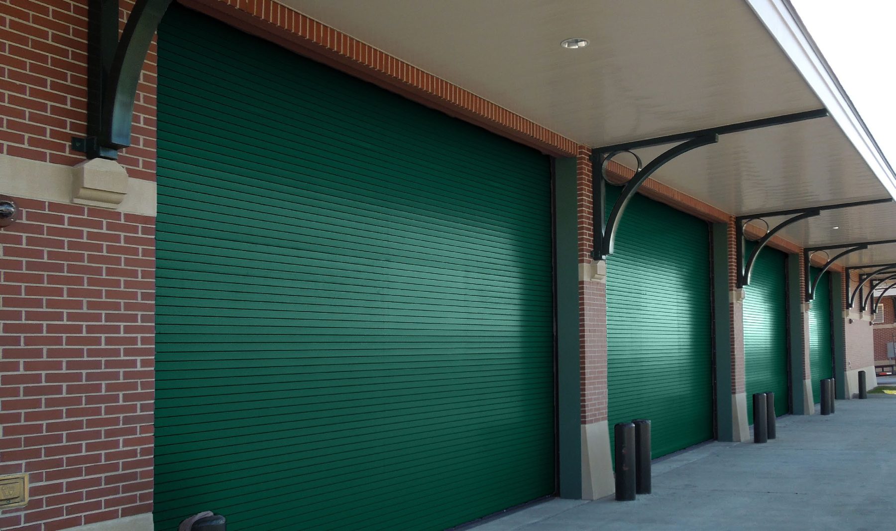 Green Janus 400HP high performance doors on a brick building under a canopy
