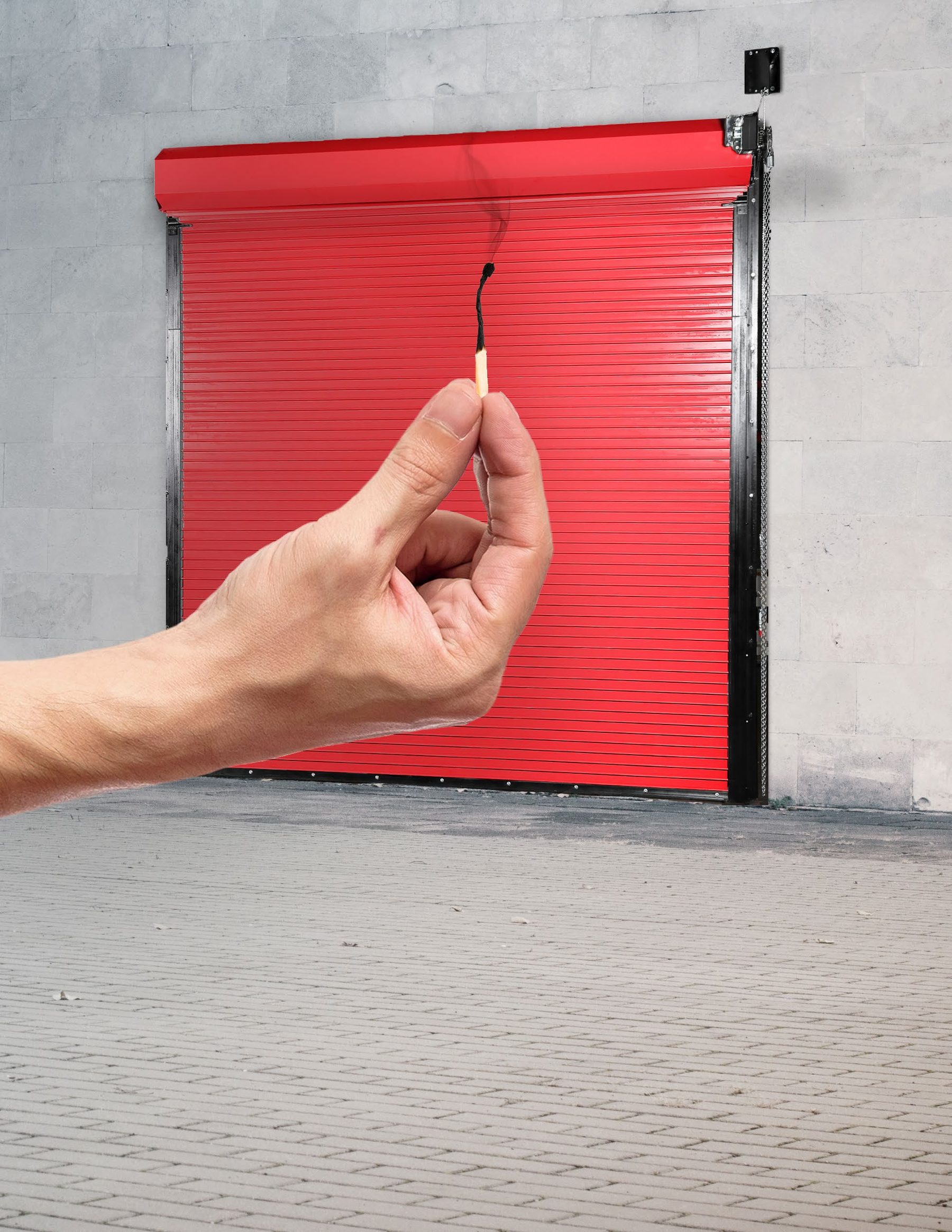 Hand holding a lit match in front of a red rolling fire door