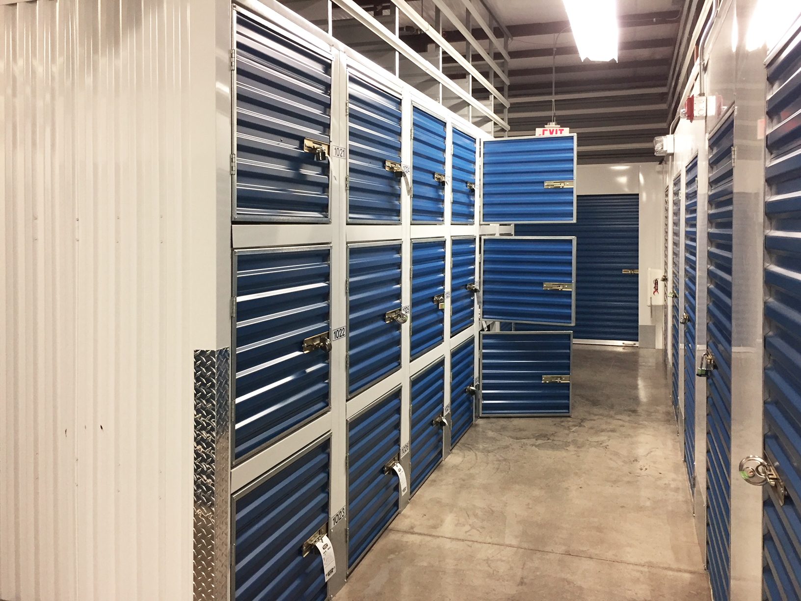 Triple-stacked blue Janus locker units in a self-storage hallway