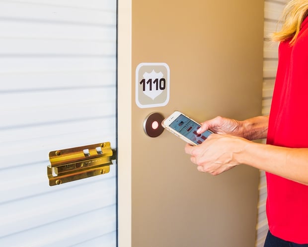 woman's hands holding cell phone using an app to enter storage unit